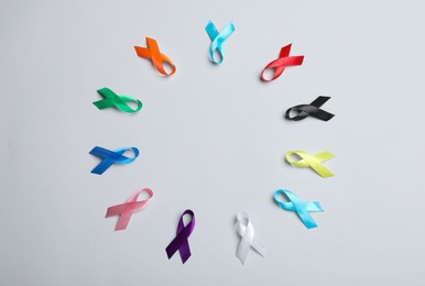 Photo of Frame of different colorful ribbons on white background, flat lay with space for text. World Cancer Day