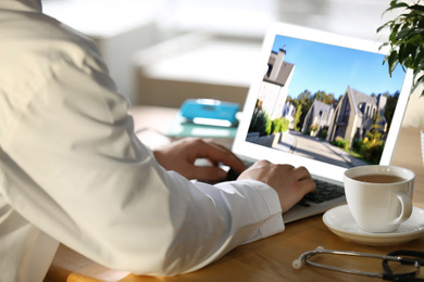 Real estate agency online service. Doctor choosing new house via laptop, closeup