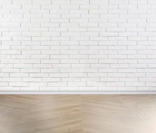 Image of Wooden floor and white brick wall indoors