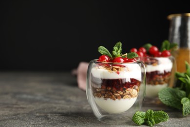 Delicious yogurt parfait with fresh red currants and mint on grey table, space for text