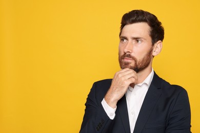 Photo of Pensive bearded man in suit looking away on orange background. Space for text