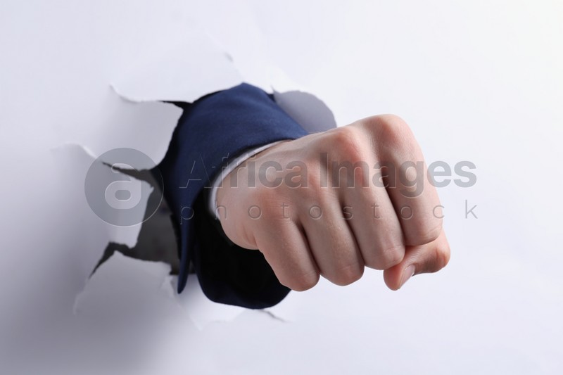 Photo of Businessman breaking through white paper with fist, closeup
