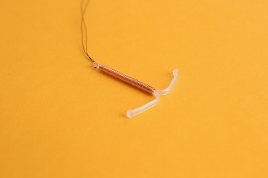 Copper intrauterine contraceptive device on yellow background