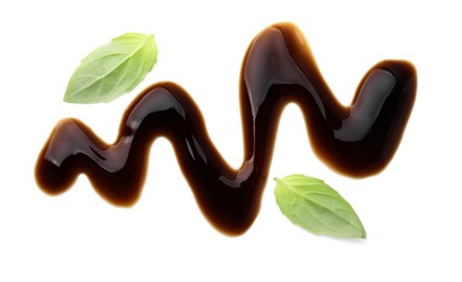 Photo of Balsamic glaze and basil leaves on white background, top view