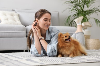 Photo of Happy young woman with cute dog lying on floor in living room