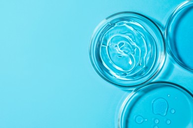 Photo of Petri dishes with liquids on light blue background, flat lay. Space for text