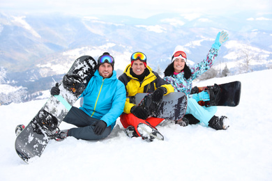 Photo of Friends with snowboards at mountain resort. Winter vacation