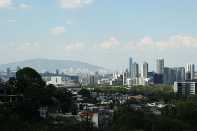 Photo of Picturesque view of city, green trees and mountains
