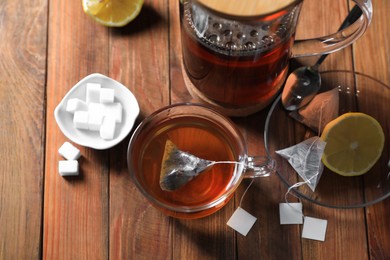 Tea bag in cup, sugar and lemon on wooden table, above view