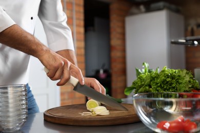 Professional chef cutting fresh leek in restaurant kitchen, closeup