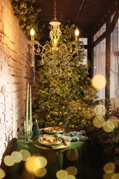 Photo of Beautiful festive table setting near Christmas tree with decor in room
