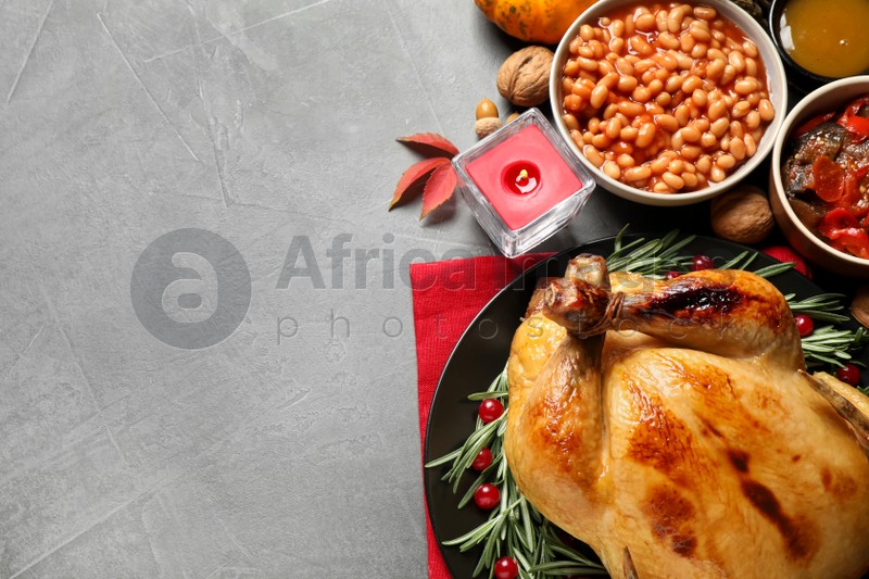 Traditional Thanksgiving day feast with delicious cooked turkey and other seasonal dishes served on grey table, flat lay. Space for text