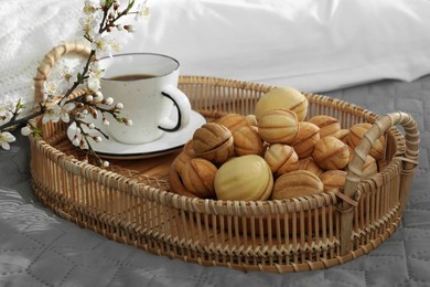 Photo of Delicious walnut shaped cookies with filling, cherry branch and cup of coffee on grey blanket. Homemade popular biscuits from childhood