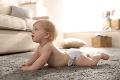 Photo of Cute little baby in diaper on carpet at home