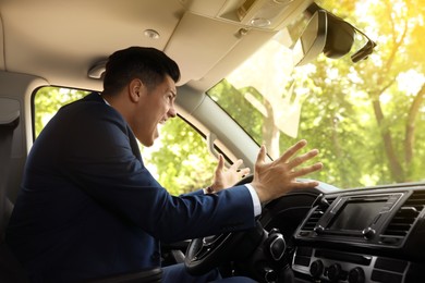 Photo of Emotional man yelling in car. Aggressive driving behavior