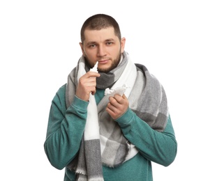 Sick man with tissue and nasal spray on white background