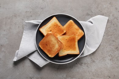 Plate with slices of delicious toasted bread on gray table, top view