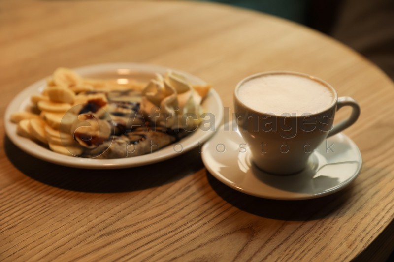 Cup of aromatic coffee and delicious desserts on wooden table