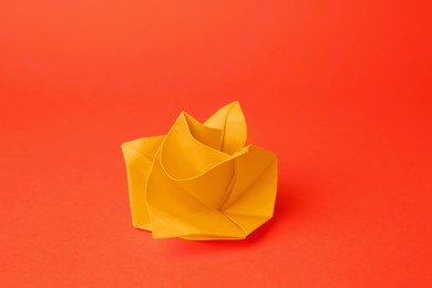 Photo of Origami art. Handmade bright paper flower on orange background