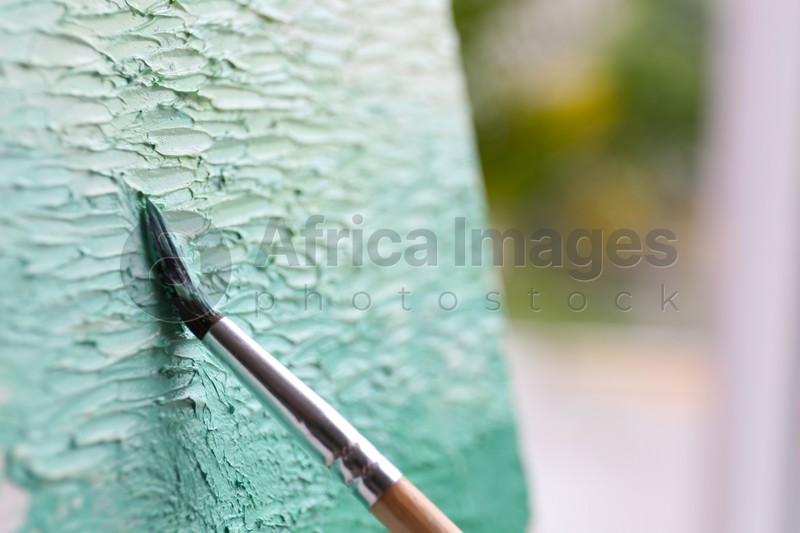 Artist painting on canvas with brush, closeup