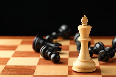 Chessboard with game pieces on black background, closeup. Space for text