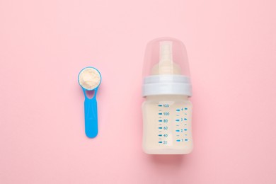 Feeding bottle with infant formula and powder on pink background, flat lay