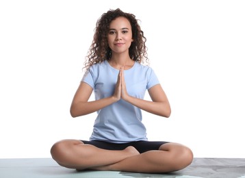 Beautiful African-American woman meditating on yoga mat against white background