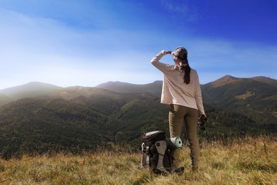 Tourist with hiking equipment and binoculars in mountains, back view