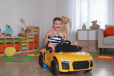 Cute little boy driving big toy car at home