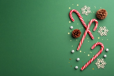 Flat lay composition with candy canes and Christmas decor on green background. Space for text