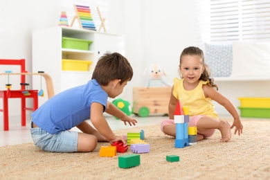 Photo of Cute little children playing with colorful blocks on floor indoors. Educational toy