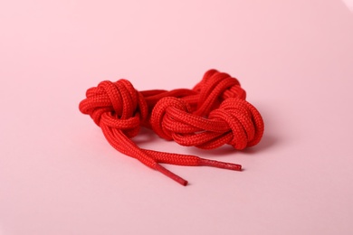 Red shoe lace on light pink background