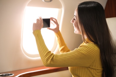 Photo of Young woman taking photo on plane. Comfortable flight