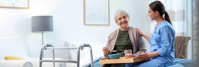 Image of Care worker serving dinner for elderly woman on geriatric hospice. Banner design