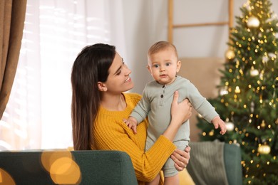 Happy young mother with her cute baby in room decorated for Christmas. Winter holiday