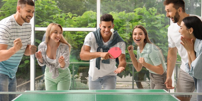 Image of Happy friends playing ping pong together indoors. Banner design