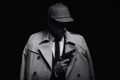 Old fashioned detective with revolver on dark background, black and white effect