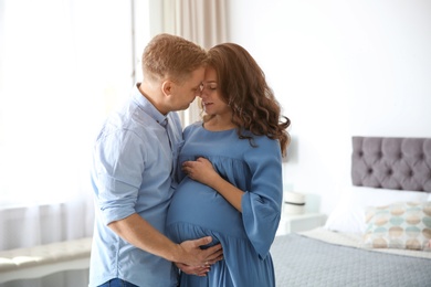 Pregnant woman with her husband in bedroom. Happy young family