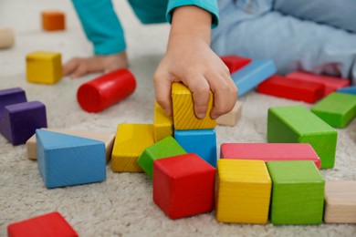 Cute little girl playing with colorful building blocks on floor, closeup