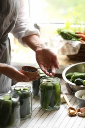 Woman putting spices into jar in kitchen, closeup. Canning vegetables
