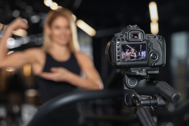 Photo of Fitness trainer recording online classes in gym, focus on camera. Space for text