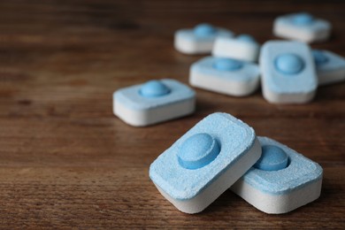 Photo of Water softener tablets on wooden table, closeup. Space for text