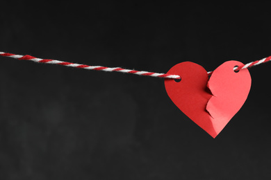 Photo of Broken red paper heart on rope against black background, space for text. Relationship problems concept