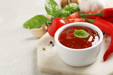 Spicy chili sauce with basil on light table, space for text