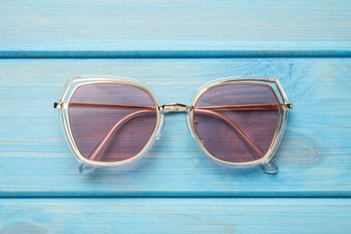 New stylish sunglasses on turquoise wooden table, top view