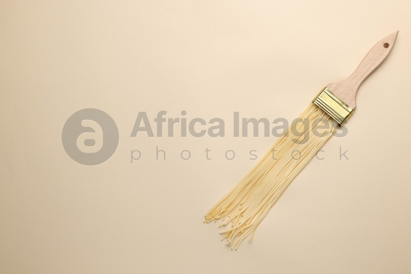 Brush painting with spaghetti on beige background, top view. Space for text. Creative concept