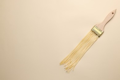 Brush painting with spaghetti on beige background, top view. Space for text. Creative concept
