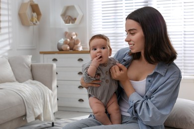 Photo of Young woman with her little baby in room at home