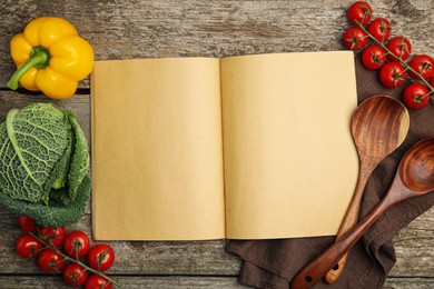 Recipe book surrounded by different ingredients on wooden table, flat lay with space for text. Cooking classes