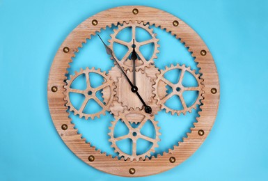 Stylish wall clock with gears showing five minutes until midnight on light blue background, top view. New Year countdown